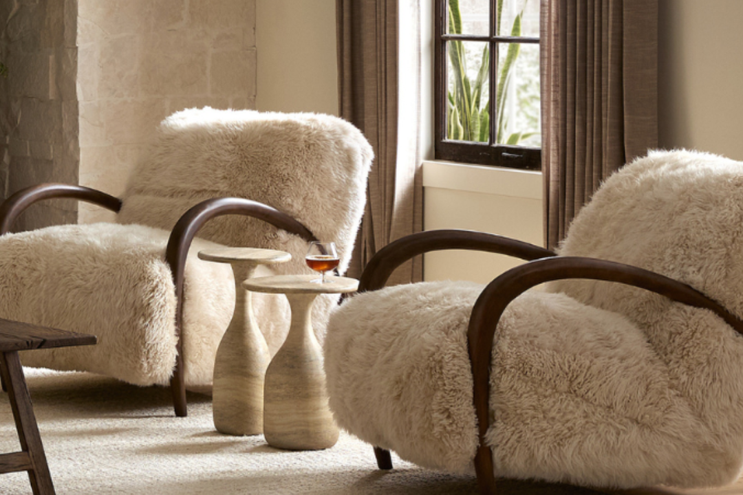 Cozy holiday living room styled with warm textured furniture, including boucle chairs, wool rugs, plush ottomans, and a winter-ready sectional.