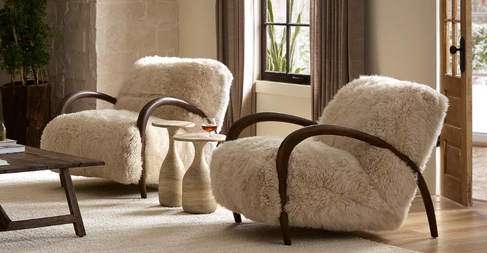 Two fluffy armchairs in a living room setting with a small table between them.